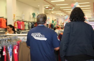 Duas pessoas de costas entrando numa loja. Na camiseta de um deles diz 