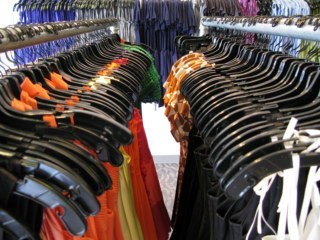 Arara de roupas com várias blusas no cabide.
