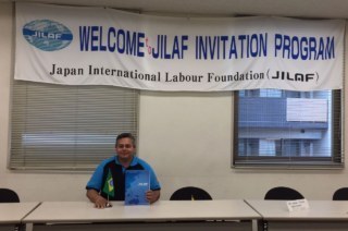 Homem sentado. Ao fundo faixa escrito: Welcome Jilaf Invitation Program