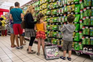 Uma mulher e duas crianças observando produtos na prateleira