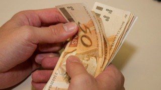 Mão segurando notas de 50 reais