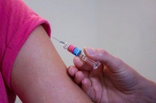 mão aplicando vacina em braço.