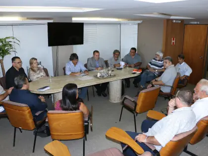 Pessoas reunidas no entorno de uma mesa para uma reunião.