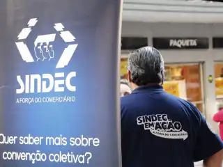 Banner com o dizer: Quer saber mais sobre convenção coletiva?. Ao fundo homem de costas com uma camiseta escrito Sindec em Ação