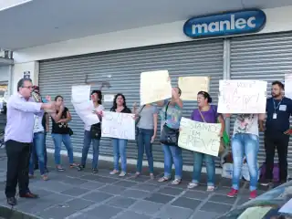 Mulher com nariz de palhaço falando no microfone. Atrás dois cartazes. Um diz: Não aguento mais, 5 meses sem salário. O outro: Justiça!