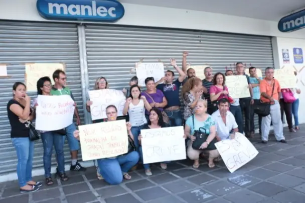 Pessoas com faixas protestando em frente a loja Manlec.