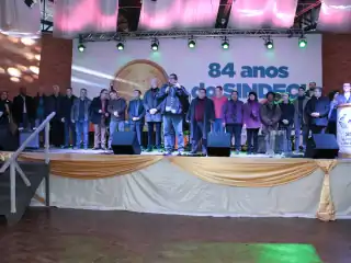 Pessoas em cima de um palco. Ao fundo diz 