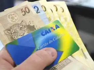 mão segurando notas de dinheiro e um cartão bancário.