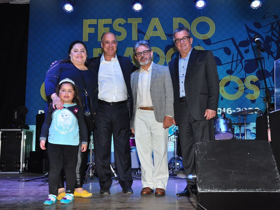 Uma mulher, uma menina e três homens num palco.