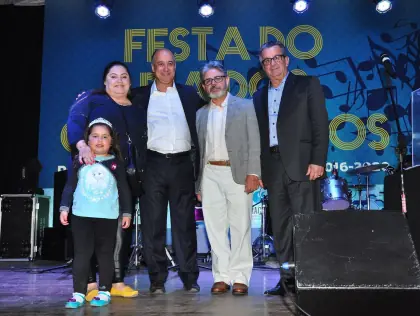 Uma mulher, uma menina e três homens num palco.