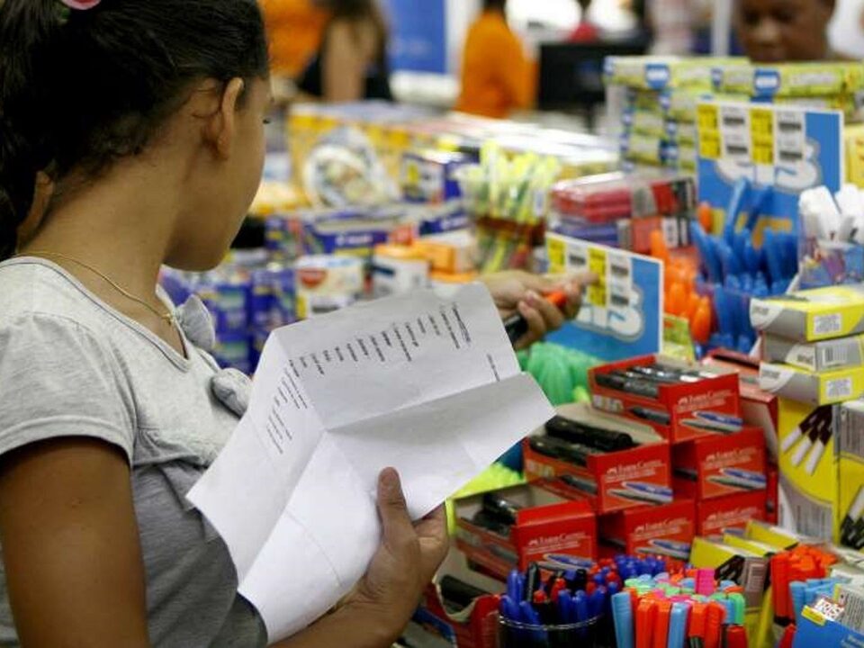 Menina com uma lista na mão olhando materiais escolares.