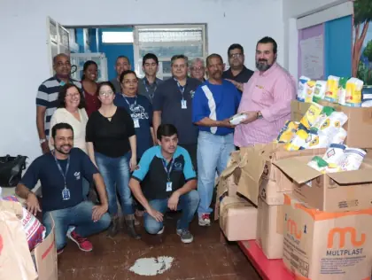 Pessoas em pé. Várias caixas com alimentos e roupas na sala.