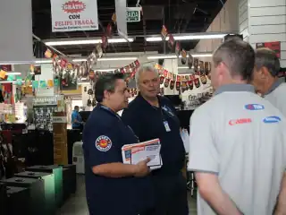 Quatro homens em pé aparentemente conversando. Um homem segura alguns papeis na mão direita.