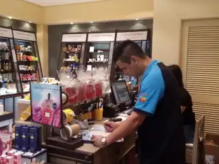 Homem fazendo anotações sobre um balcão de loja de cosméticos.