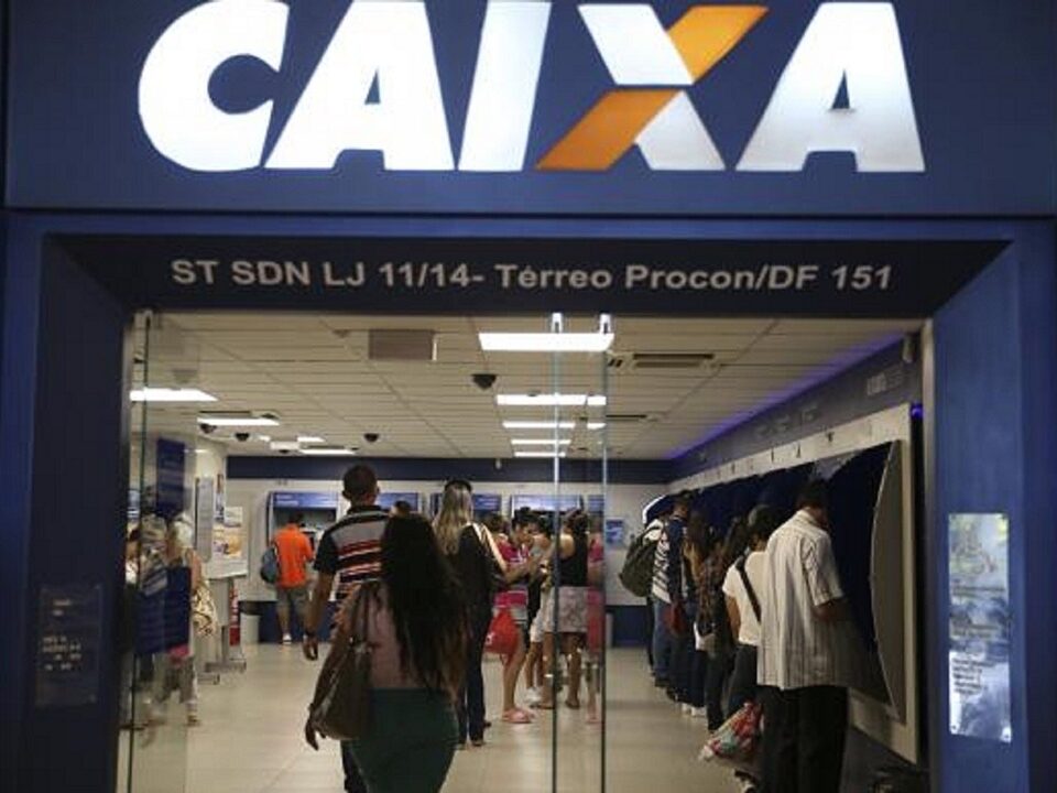 Faixada de uma agência da Caixa Econômica Federal. Pessoas entrando